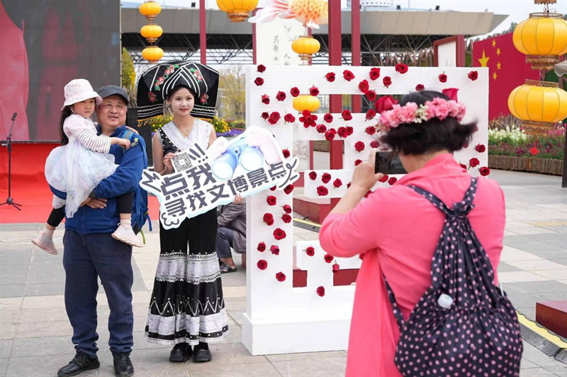 人员以及云南省文旅志愿者们手持"点我咨询"系列的手举牌在游客中穿行