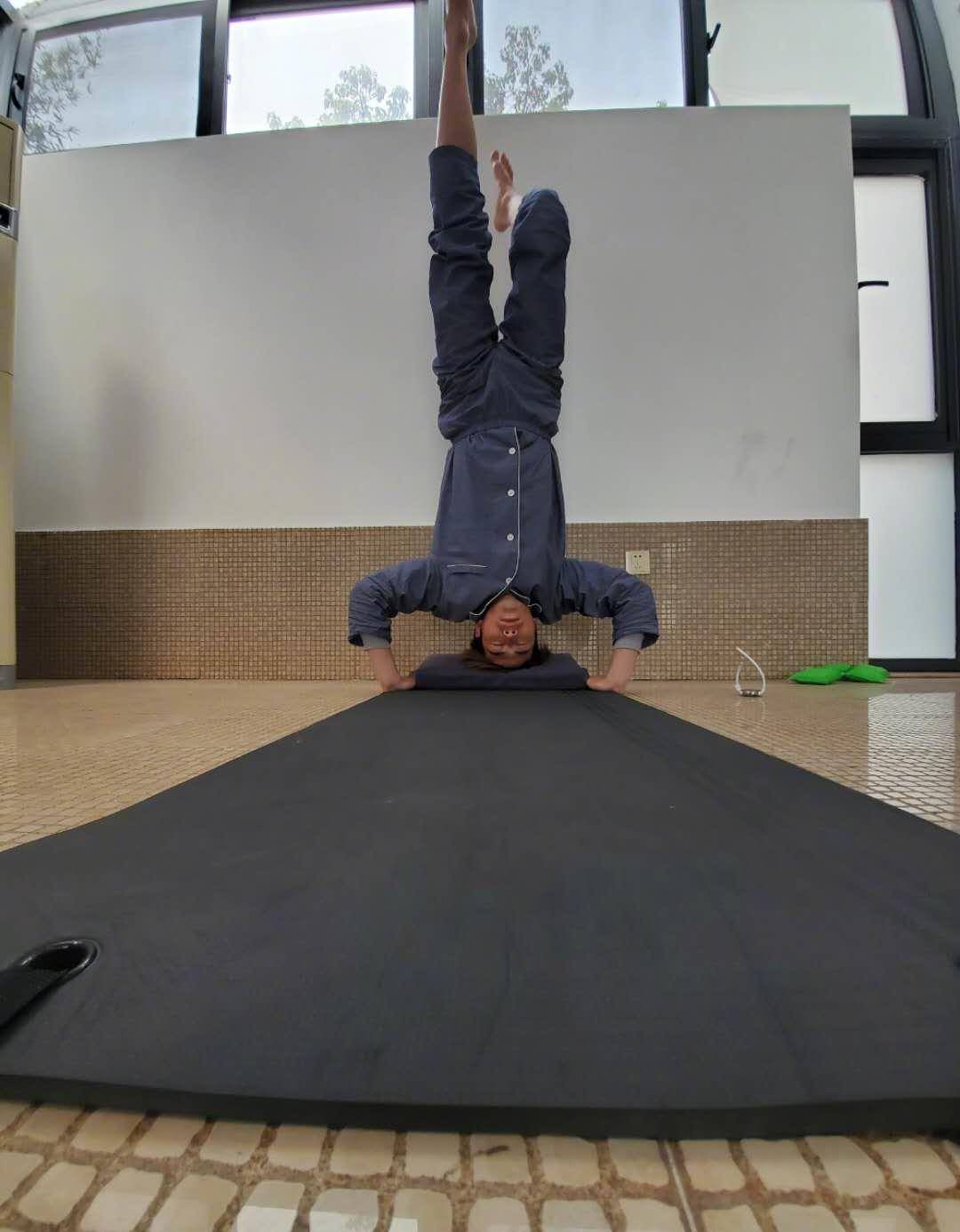 照片当中的陈学冬处于倒立的状态,地上只铺上了一个瑜伽垫,两只脚是在