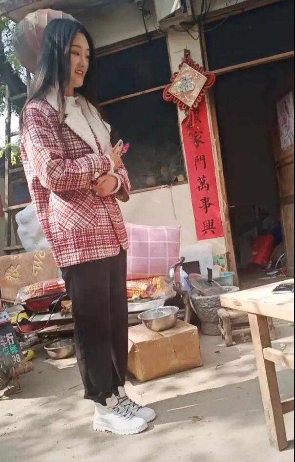 大衣哥的儿媳妇拿着手机站在一旁,呆呆的看着大衣哥夫妇忙碌做饭,院子