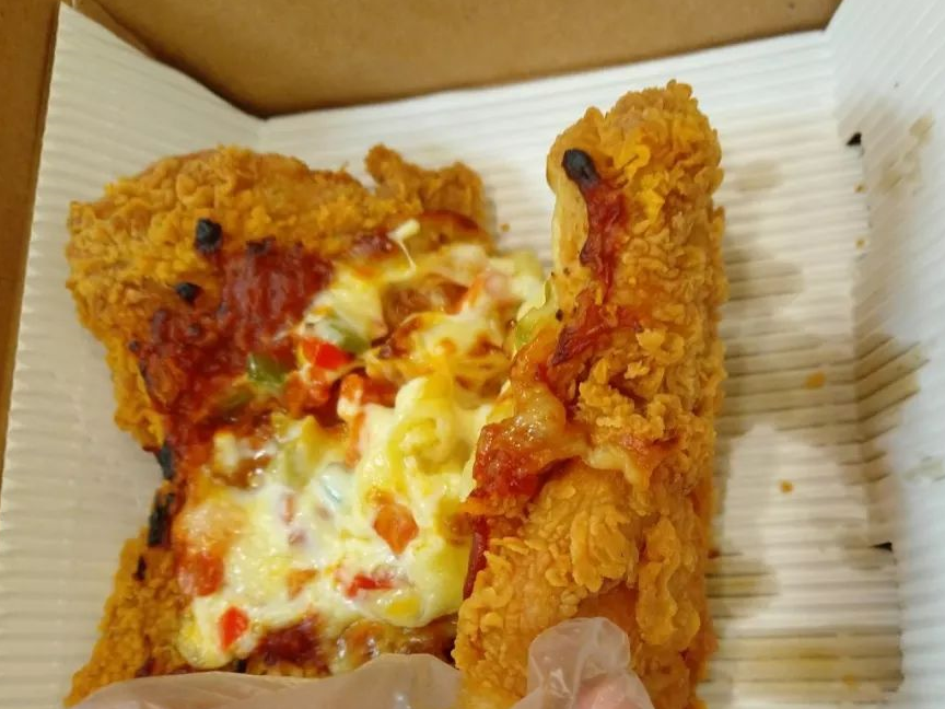 饼底是炸鸡腿排,之上是的红色固体类似被烤过的番茄酱,最上则是芝士和