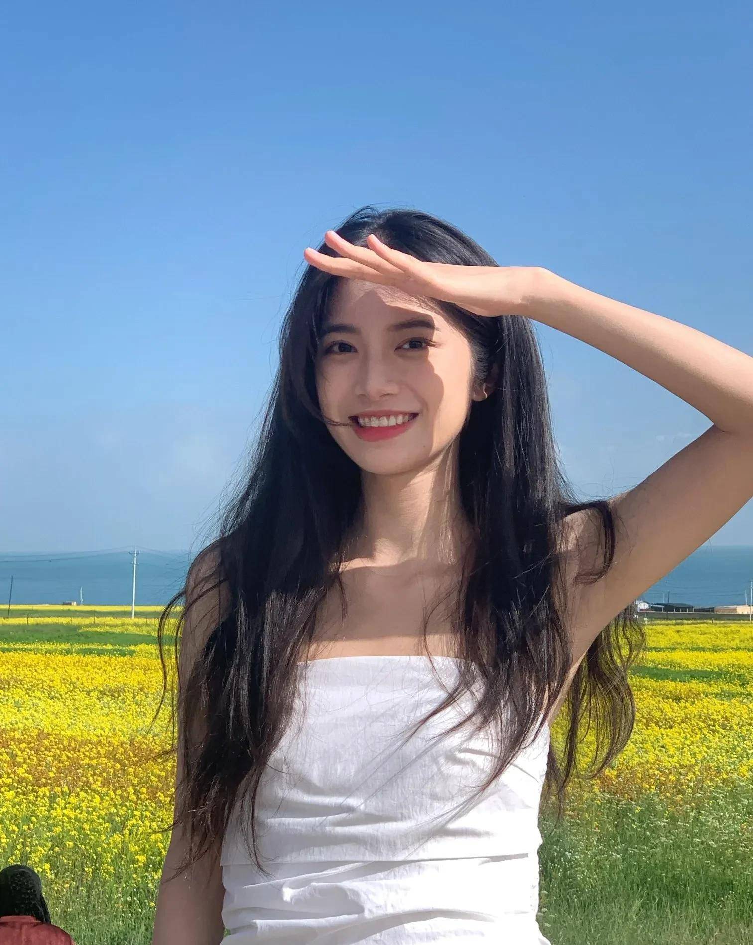 阳光下的微笑:美丽女子油菜花田边摄影