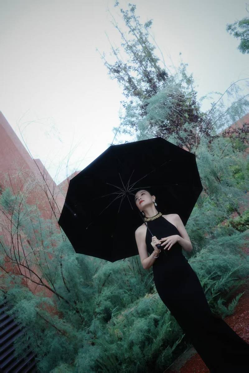 倪妮穿挂脖裙身材曼妙 撑黑伞漫步雨中尽显故事感