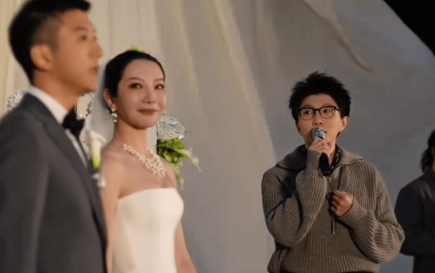 友人の結婚式でマイクを持ち、スピーチする毛不易。手前に新郎新婦が写る