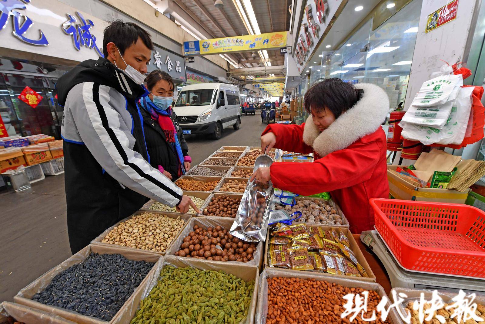 在南京做坚果生意20多年,一身红色工作服的老板娘正站在一箱箱炒货前
