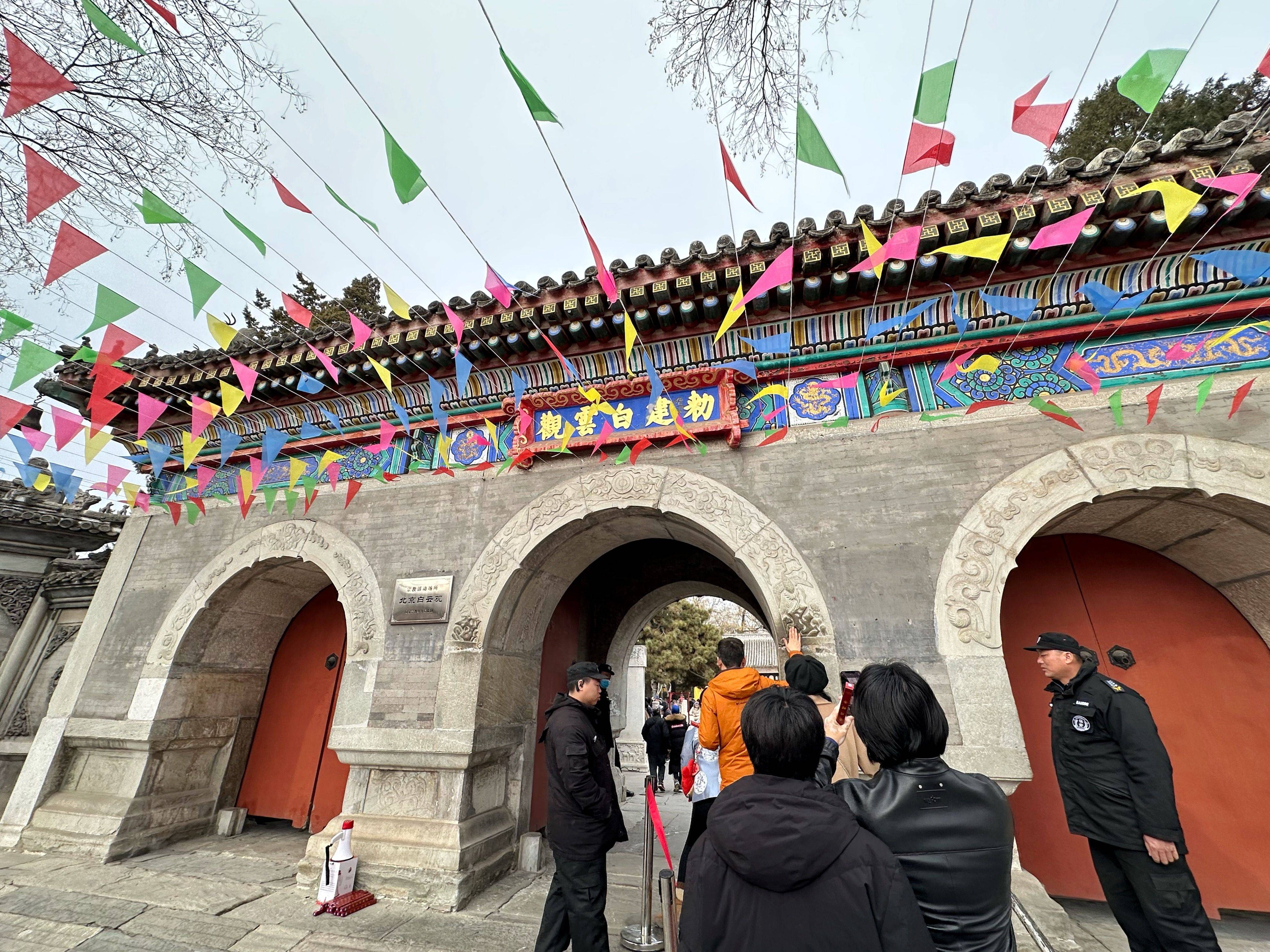 北京市民初五白云观排队摸石猴,窝风桥下工作人员戴着头盔扫铜钱_游客