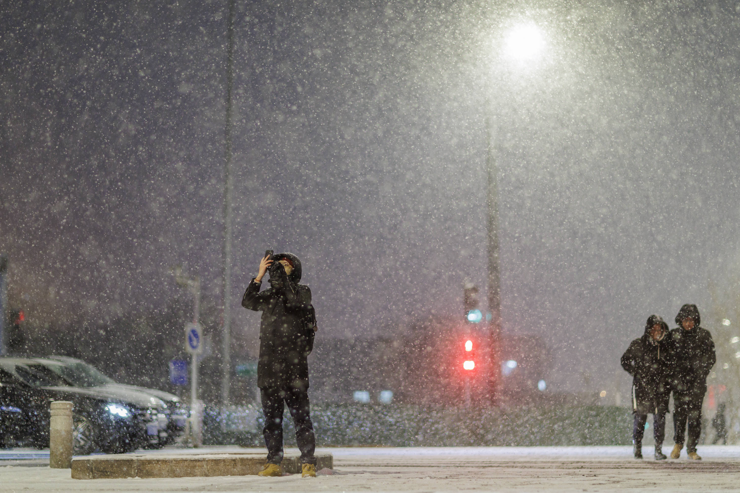 通州果园,市民在路侧拍摄大雪纷飞的场景东四十条,路灯下的片片飞雪