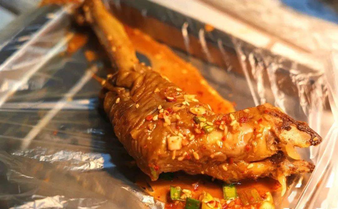 手捧冒着热气的羊蹄,卤汁顺着蹄缝渗出,滴在蒙着透明薄膜的餐桌之上.